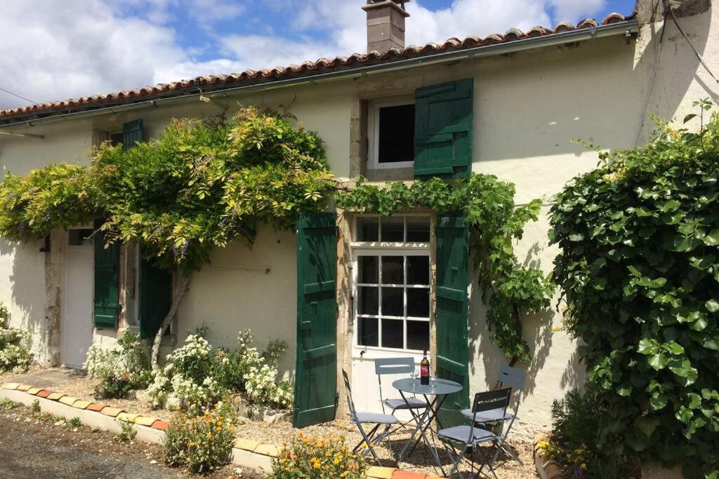 una casa bianca con persiane verdi e un tavolo di La Maison Glycine a La Villedieu