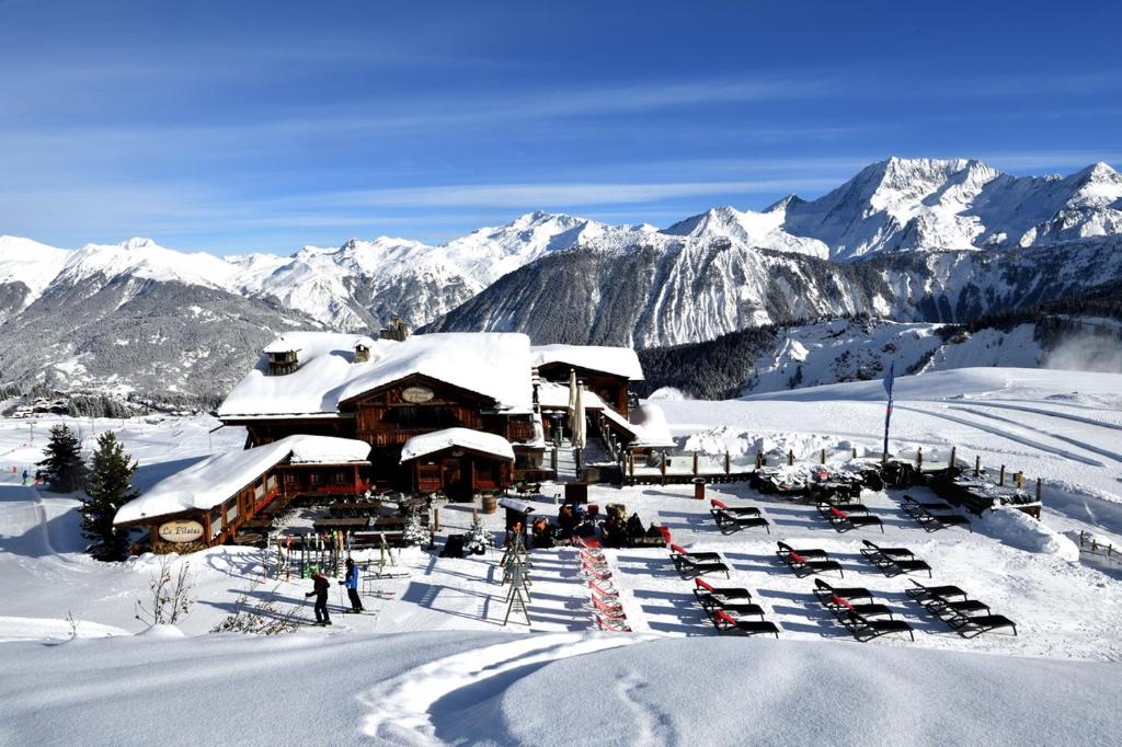 un lodge de ski avec des voitures garées dans la neige dans l'établissement Hôtel 3 étoiles -Restaurant Le Pilatus Courchevel, à Courchevel