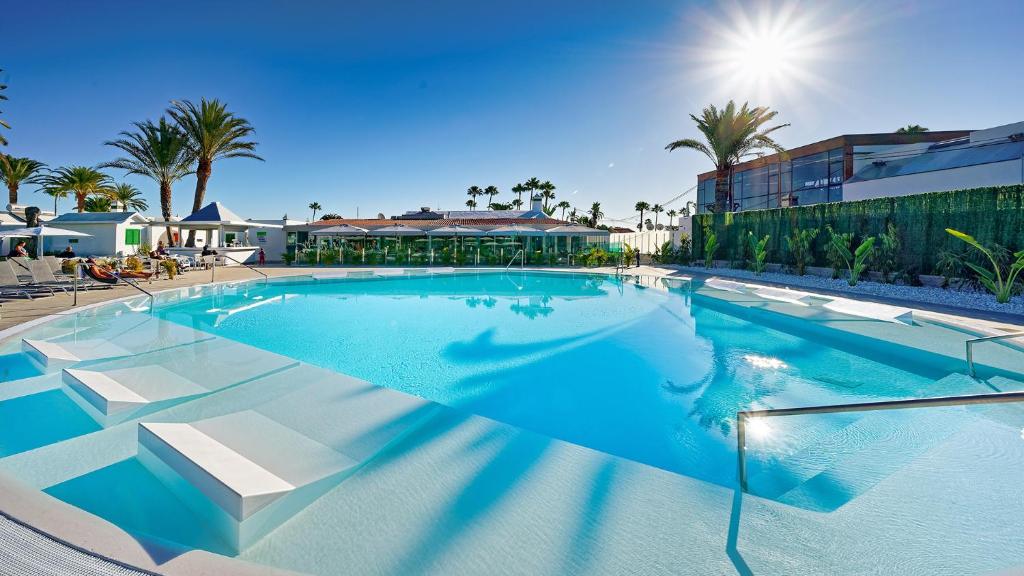 a large swimming pool in a resort with palm trees at Canary Garden Club in Maspalomas