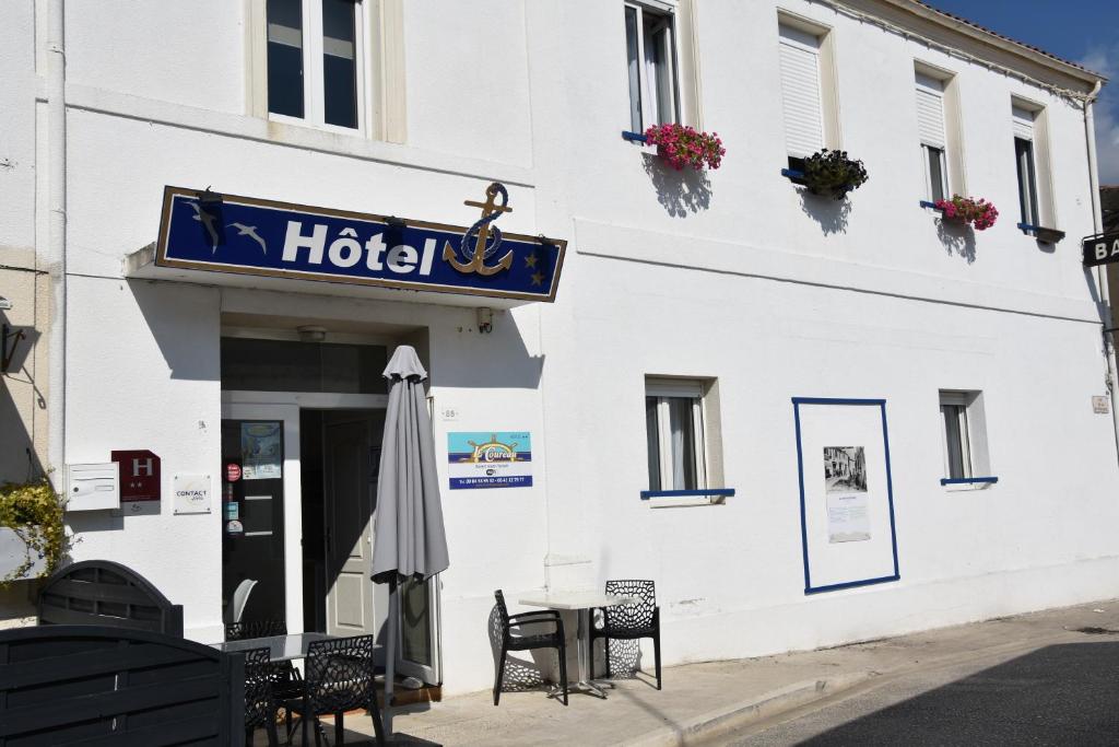 um hotel com uma mesa e cadeiras e um guarda-sol em Hotel Le Coureau em Saint-Trojan-les-Bains