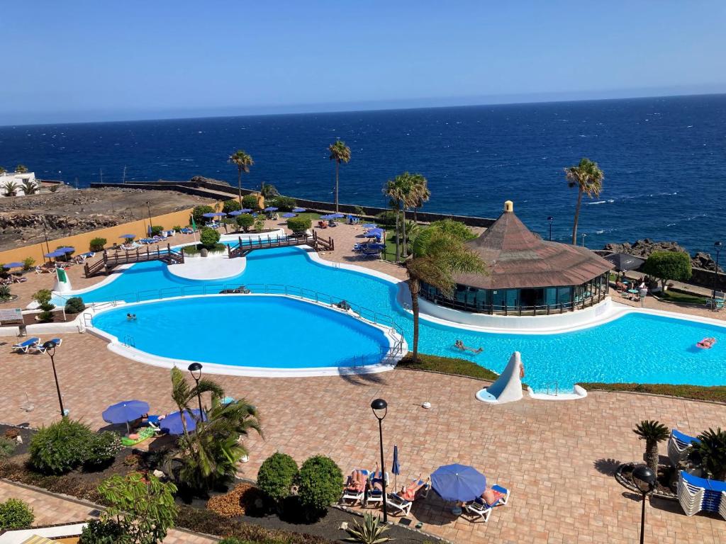 a swimming pool with the ocean in the background at Apartamentos Rocas del Mar in Costa Del Silencio