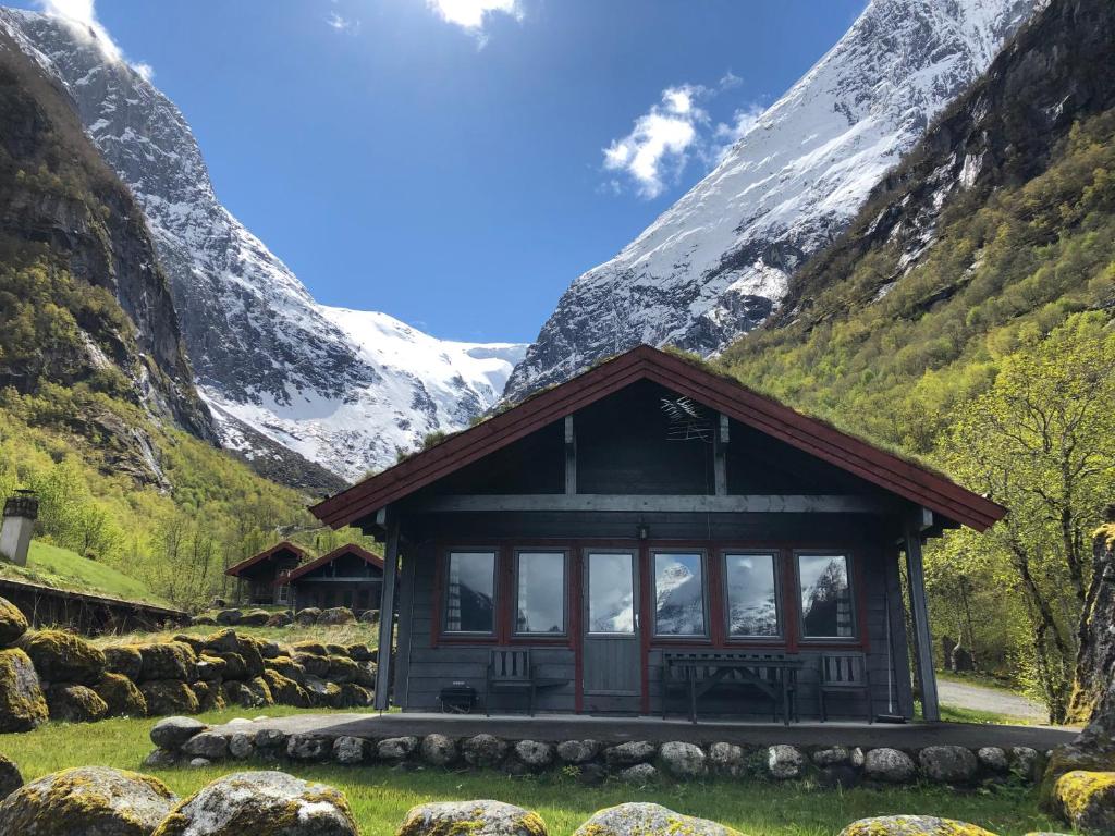una pequeña cabaña con una montaña en el fondo en Melkevoll Bretun Camping en Briksdalsbre