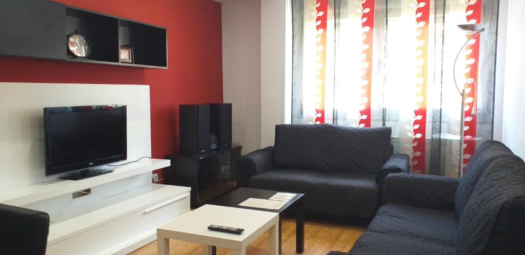 sala de estar con 2 sillas y TV de pantalla plana en Apartamento Los Lirios Logroño, en Logroño