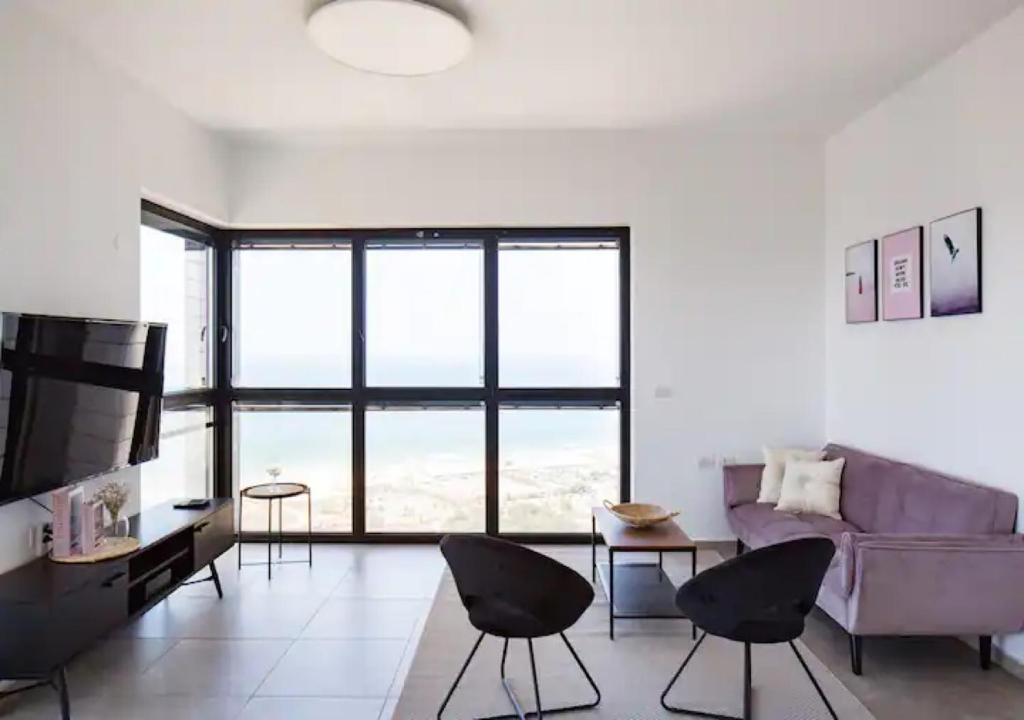 una sala de estar con un sofá púrpura y sillas en O&O Group- Modern Luxury APT-Mesmerizing Sea Views, en Bat Yam