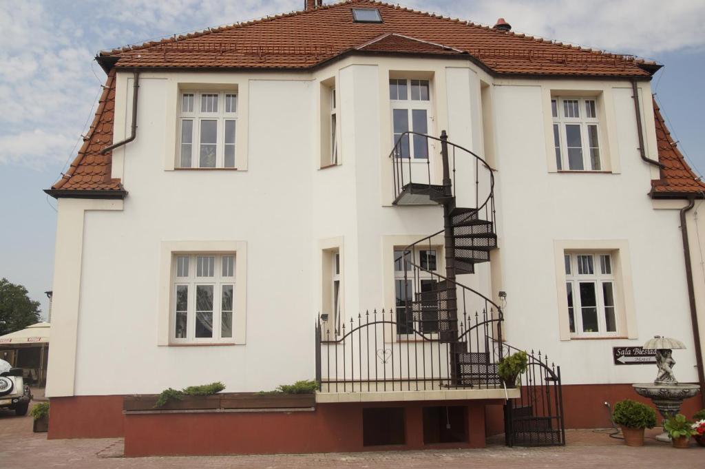 ein weißes Haus mit einer Wendeltreppe davor in der Unterkunft Pałacyk w Pakości Hotel in Pakość