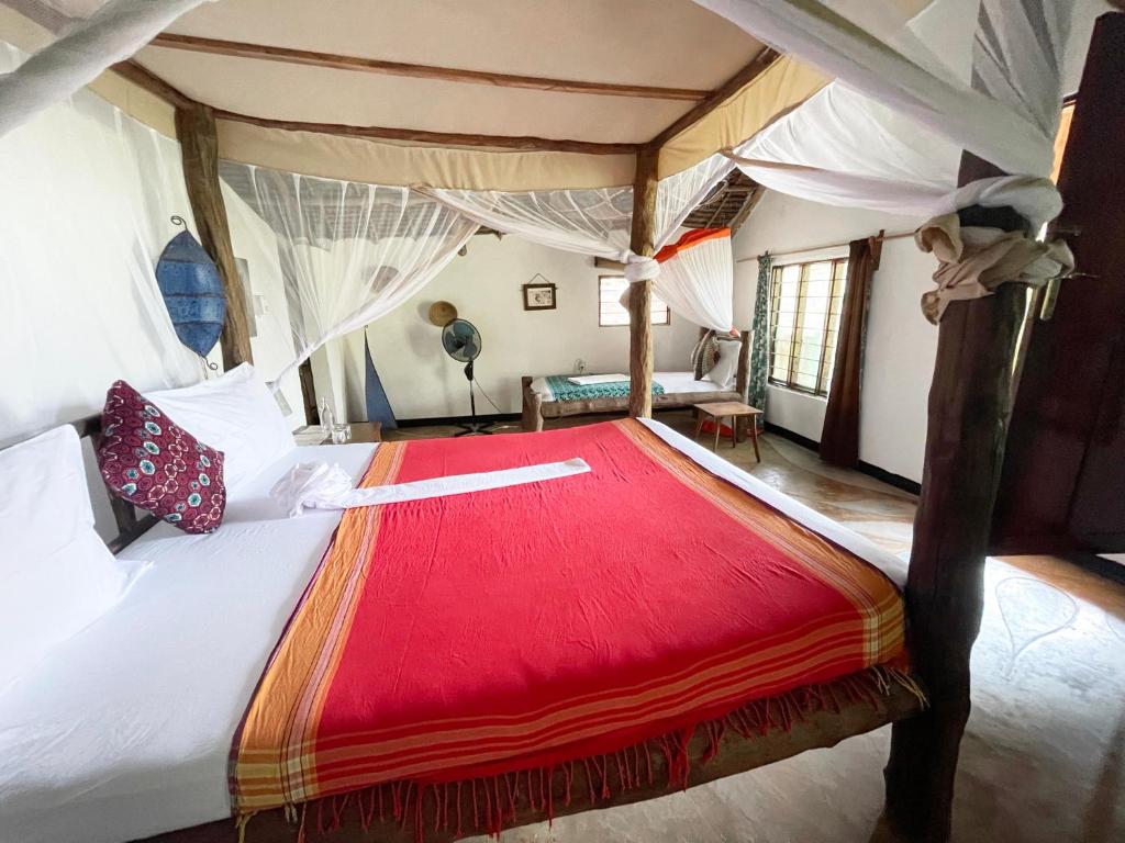 a bedroom with a large bed with a red blanket at Bellevue Zanzibar in Bwejuu