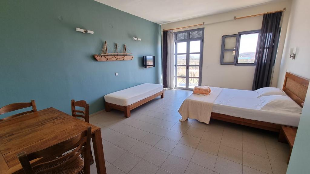 a room with two beds and a table and a desk at Domatia me Thea in Elafonisos