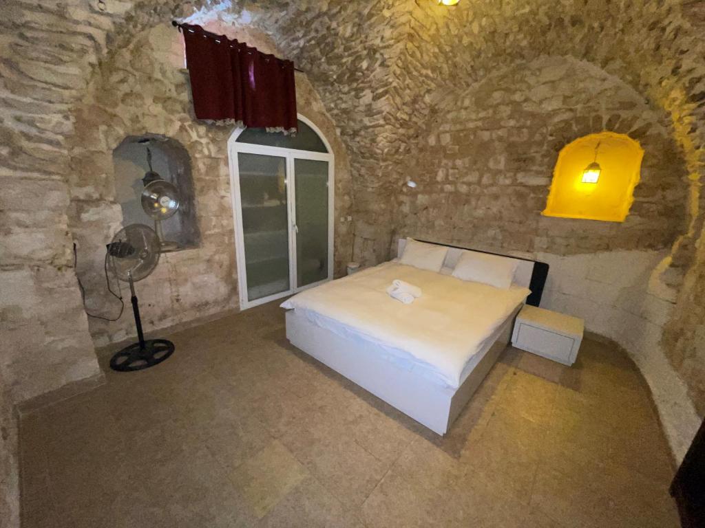 1 dormitorio con 1 cama en una pared de piedra en Michael Zimmer, en Safed