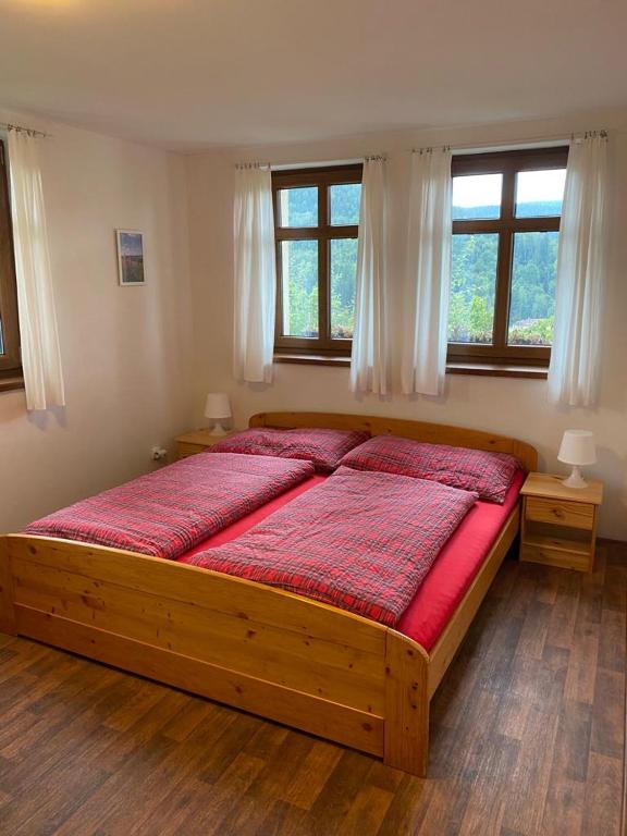 a large bed in a bedroom with two windows at Chalupa u Josefa in Josefuv dul