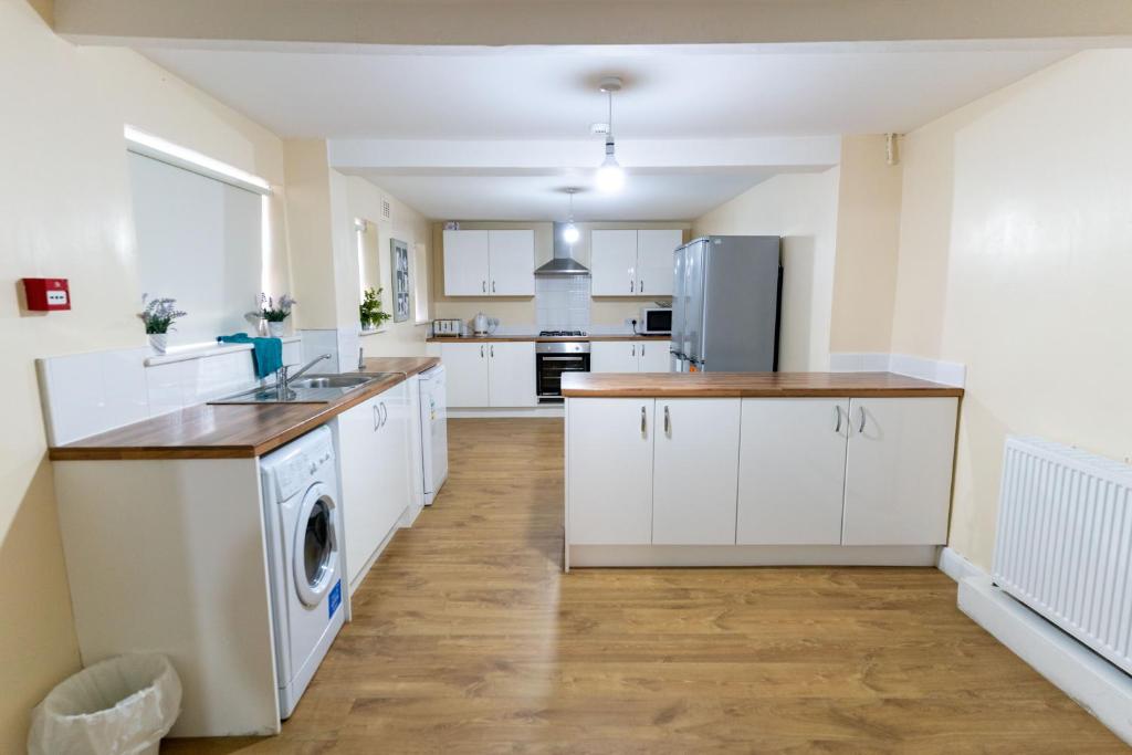 a kitchen with white cabinets and a washer and dryer at Newcastle City Apartment All En-Suite in Elswick