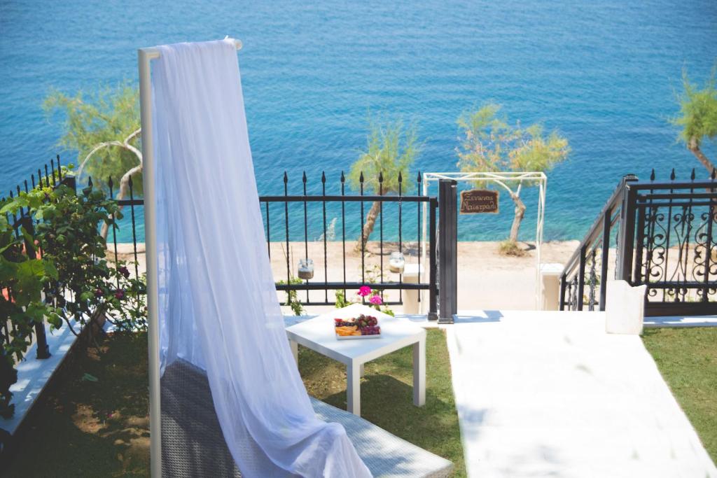 a patio with a white curtain and a table and the ocean at Maistrali Pension in Skala Marion