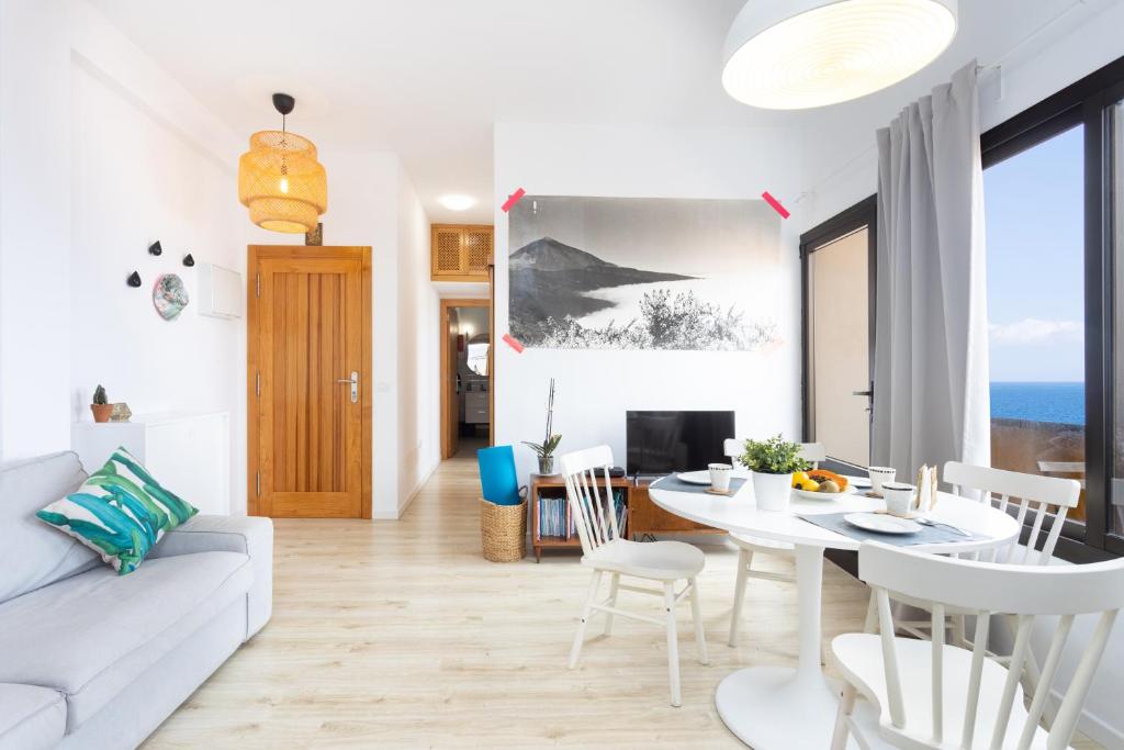 een woonkamer met een witte bank en een tafel bij Home2Book Charming Apartment Bajamar in Bajamar