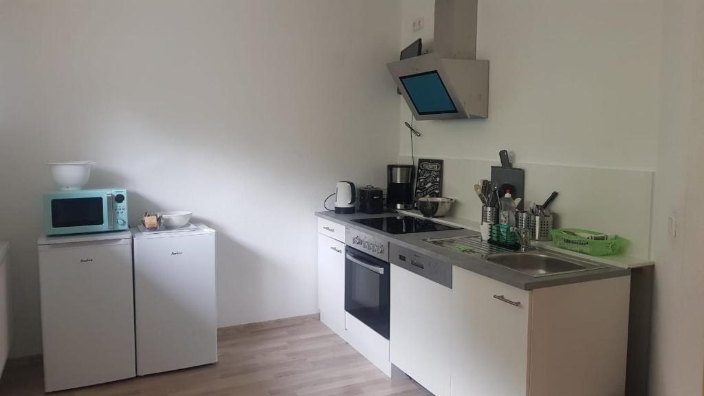 a kitchen with white cabinets and a sink and a microwave at Niederdreisbacher Hütte - moderne Doppelzimmer - EINZELBETTEN - in Niederdreisbach