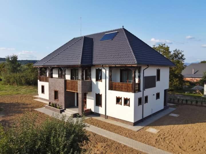 una grande casa bianca con il tetto nero di Pensiunea Casa Doamnei a Tămaia