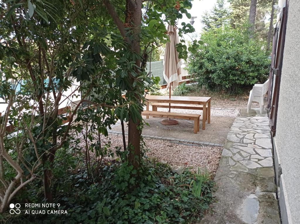 a wooden bench and an umbrella in a garden at El terret in Sigean