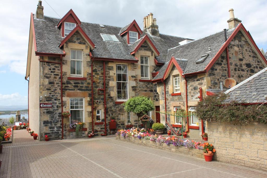 una vieja casa de piedra con flores delante en Glenbervie Guest House en Oban