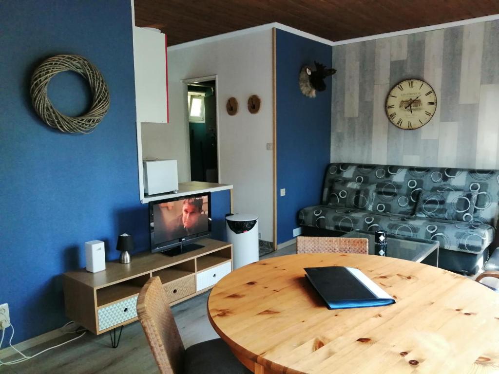 a living room with a wooden table and a television at Au repos de Zoé in Waulsort
