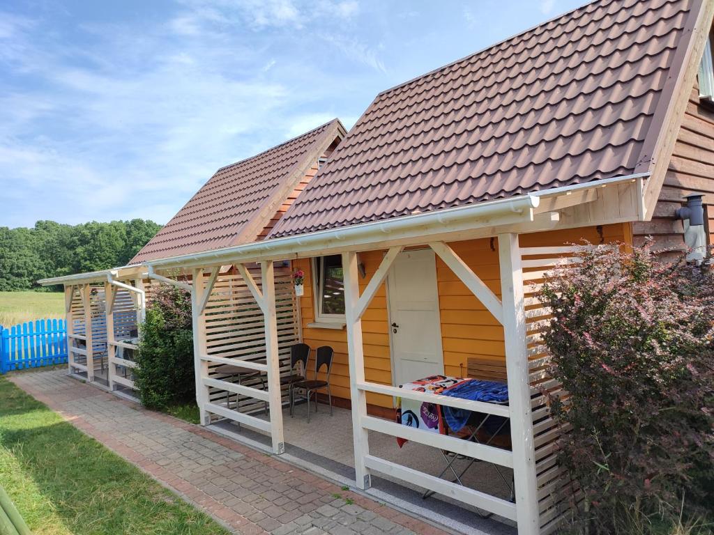 a house with a pitched roof with a porch at Piętrowe DOMKI KLIF 6os,Cudnie Bezludnie dzika plaża łąka bociek cisza szlaki rowerowe pieski 25zl in Debina