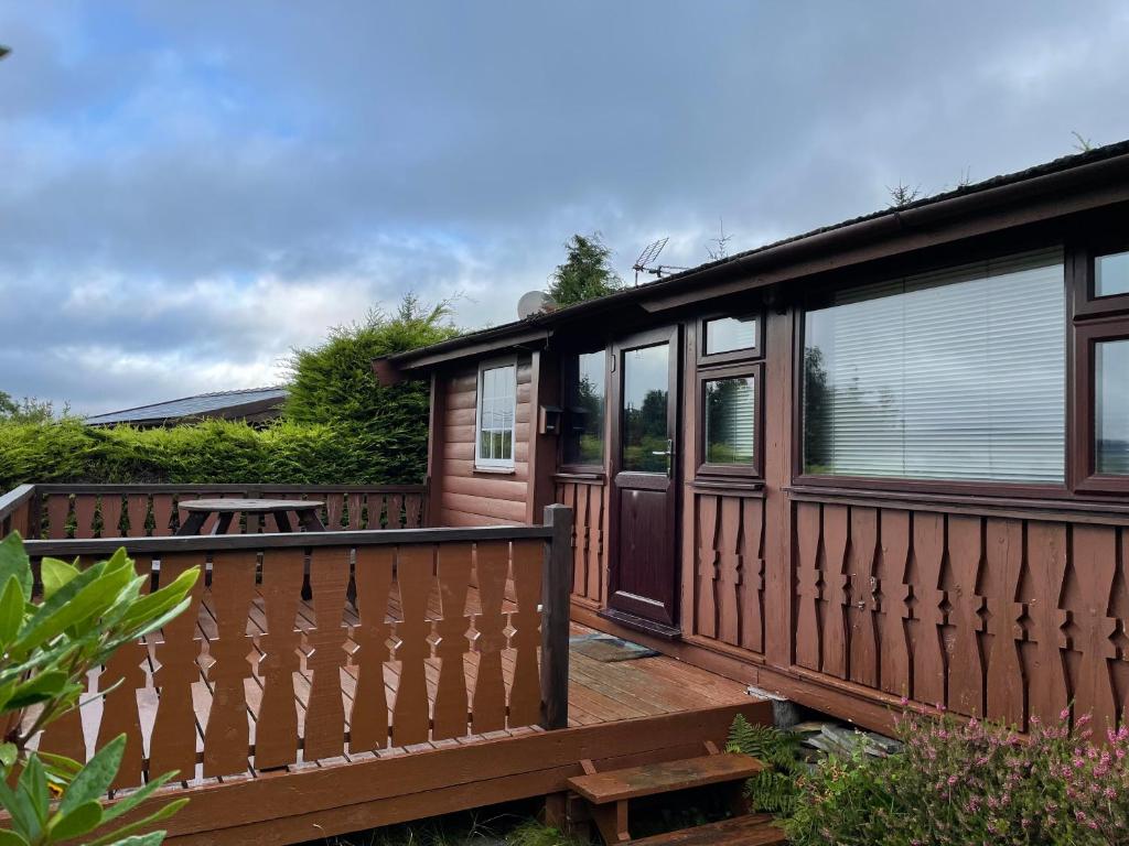 Casa con terraza de madera con mesa en Cosy 2 bedroom Log Cabin in Snowdonia Cabin151 en Trawsfynydd