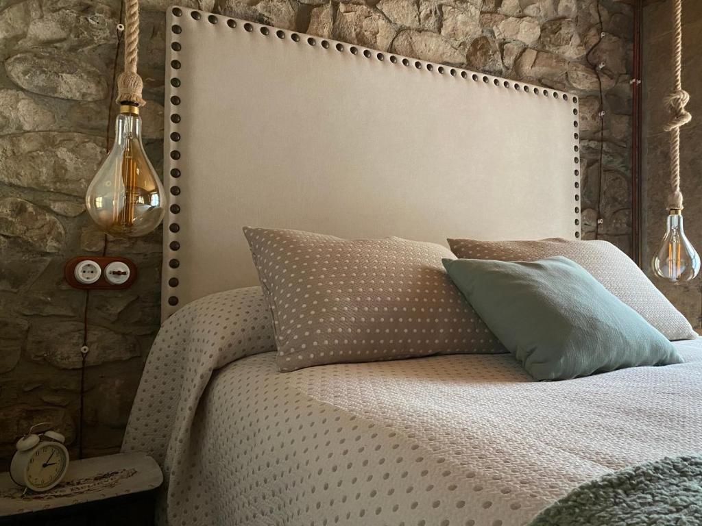 a bedroom with a white bed with a stone wall at El Apartamentin - en el corazón del Parque Natural de Redes in Ríoseco