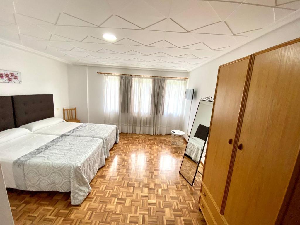 um quarto com uma cama grande e piso em madeira em Garden Lodge Hostal Evencio em Ribadavia