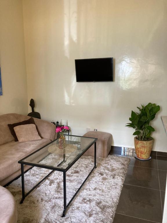 ein Wohnzimmer mit einem Sofa und einem Glastisch in der Unterkunft Chez Camille a Zac Mbao in Diokoul