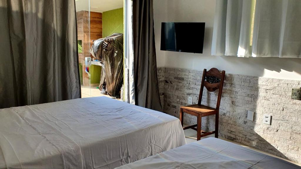 ein Schlafzimmer mit einem Bett, einem Stuhl und einem Spiegel in der Unterkunft Shallow Beach in Búzios