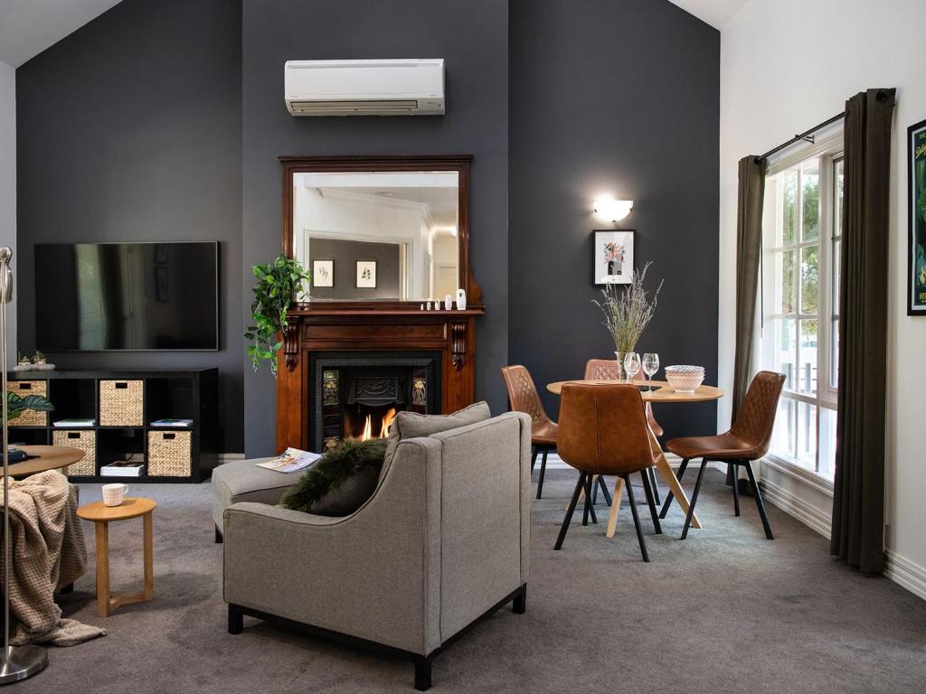 a living room with a fireplace and a table with chairs at Lucini Cottage- wood fire and bush views in Hepburn Springs
