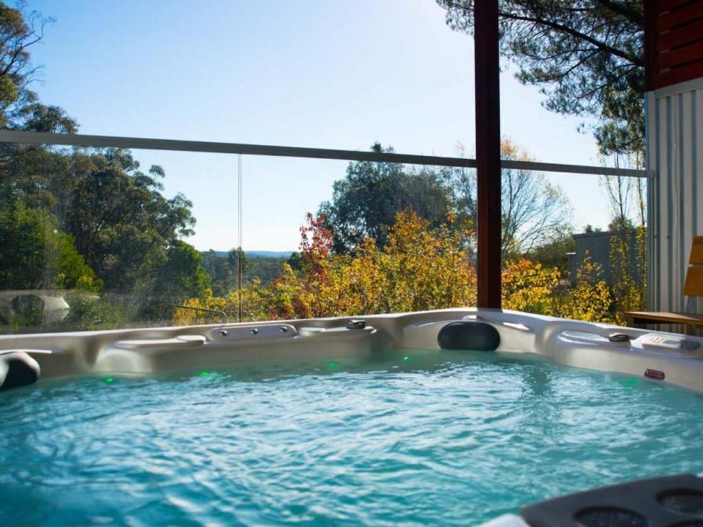 a hot tub in a room with a large window at Artemis Retreat in Daylesford