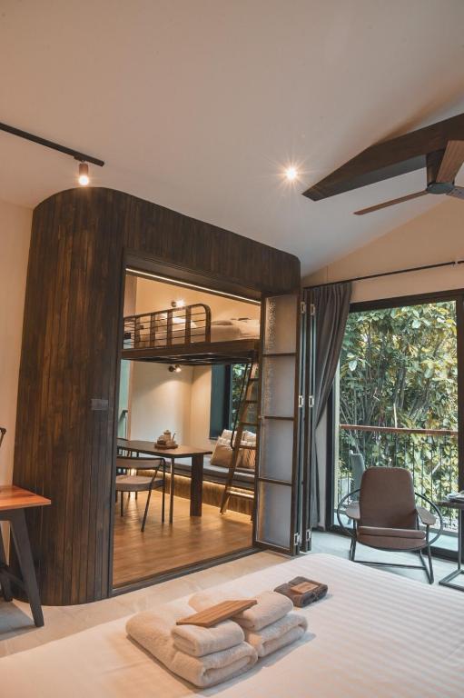 A bedroom overlooking a compact dining area and a leafy balcony.