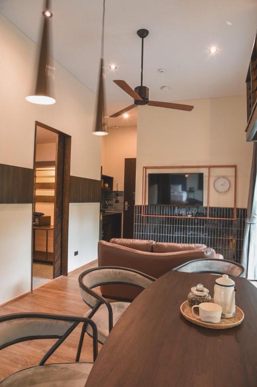 A shared lounge and dining space with leather seating, tea service, and a ceiling fan.
