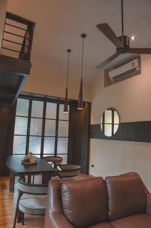 A high-ceilinged lounge and dining area with leather seating, a table, and ceiling fan.