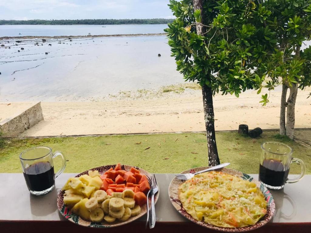 een tafel met een bord eten en een bord groenten bij Aloha Guest House Nias in Hilibotodane