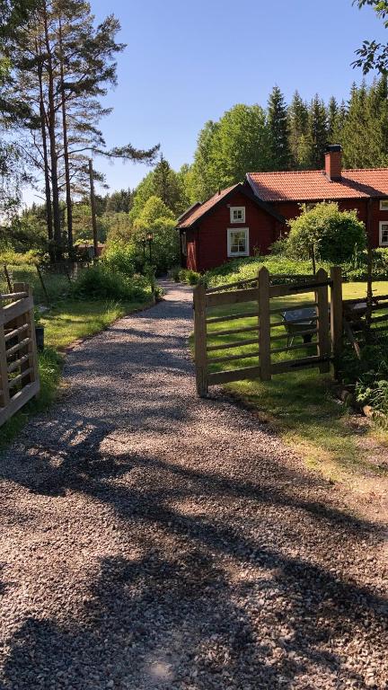 a road with a fence and a red barn at Egen stuga med delat badrum in Norrtälje