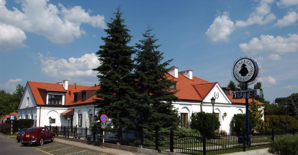 Biały budynek z zegarem przed nim w obiekcie Hotel "Zajazd Napoleoński" w Warszawie
