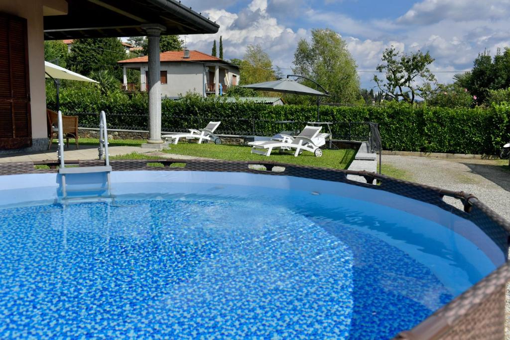 a large blue pool with two chairs and a house at Villa Vittoria in Erba