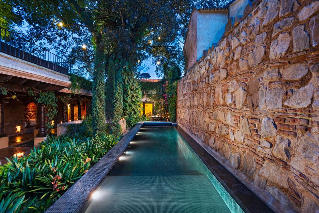 a swimming pool in front of a stone wall at El Convento Boutique Hotel in Antigua Guatemala