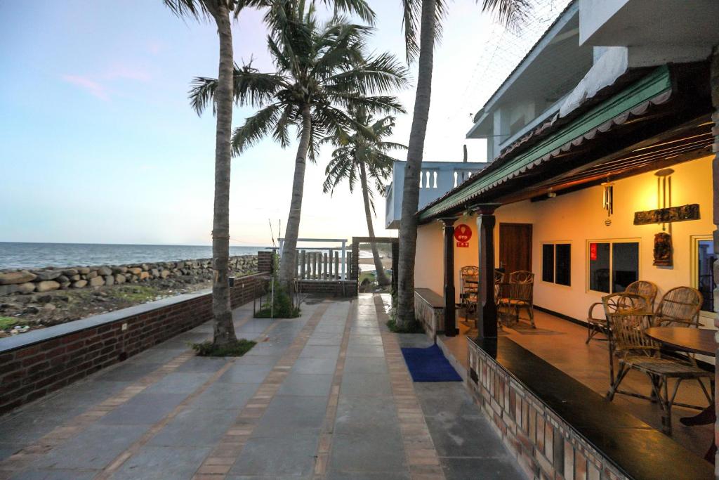 een stoep naast een gebouw met palmbomen en de oceaan bij Mermaid Island Beach Resorts in Pondicherry