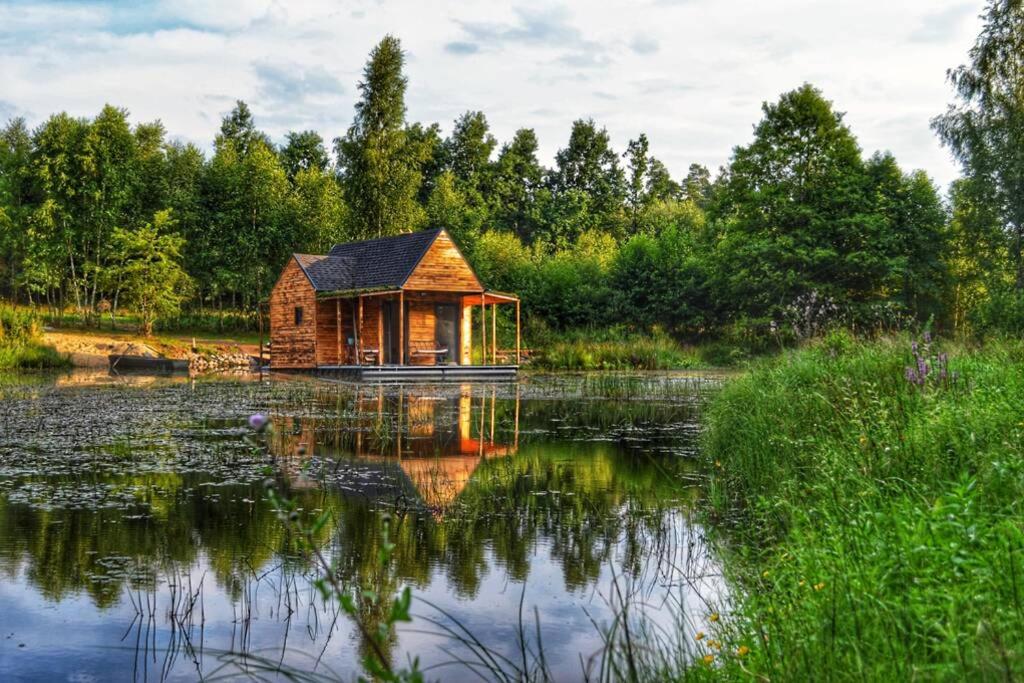 een hut op een meer met zijn reflectie in het water bij heather hut, off-grid cottage on a pond+2 ha in Darżkowo