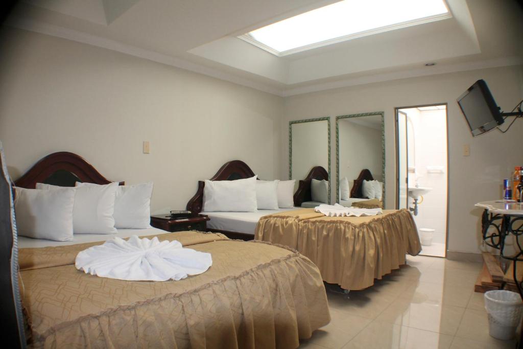 a hotel room with two beds and a mirror at Hotel Business in Bogotá