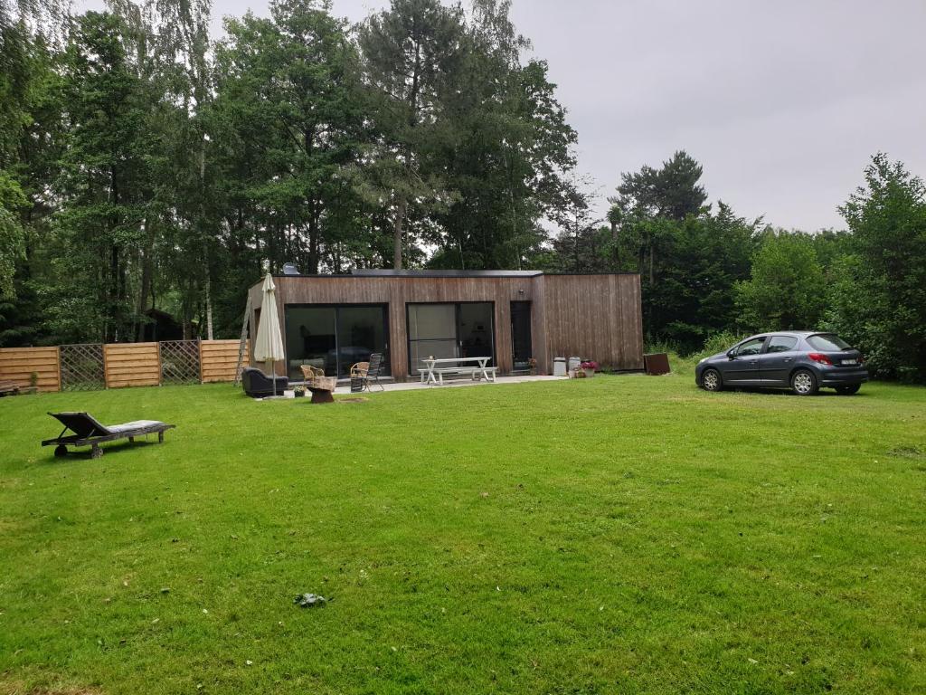 a small cabin in a field with a car parked in front at Eden in Sint-Pauwels