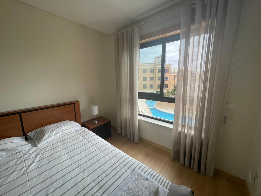 a bedroom with a bed and a window with a swimming pool at Casa da Praia in São Martinho do Porto