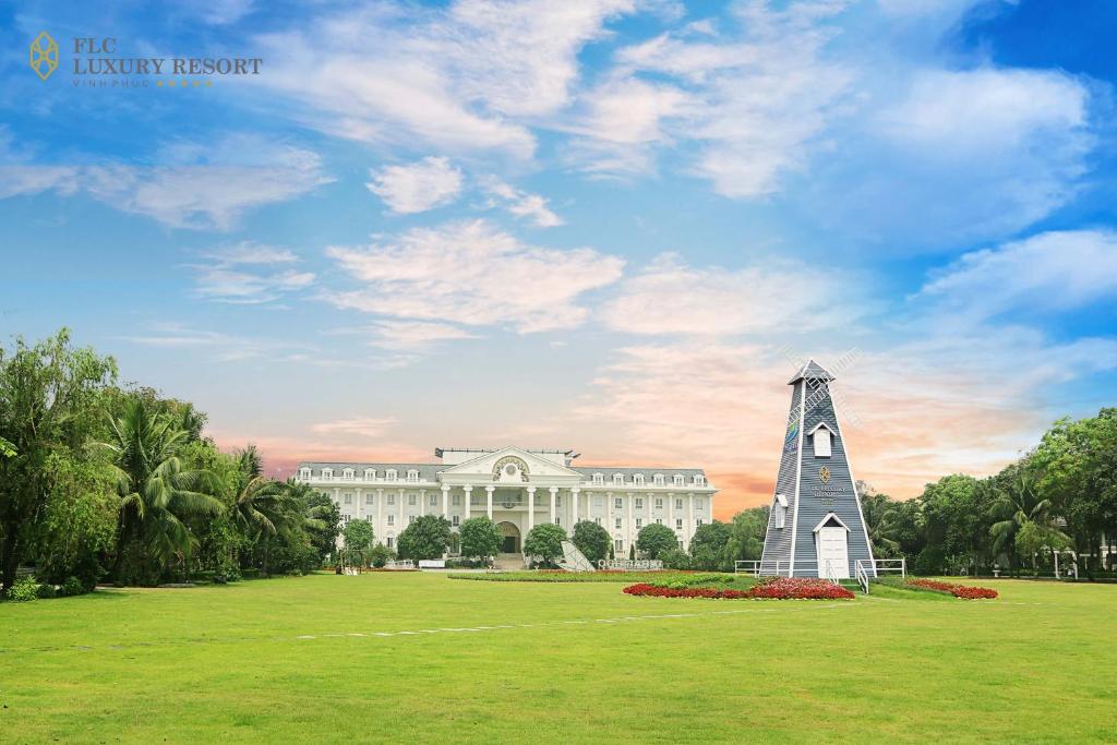 un edificio con una torre de reloj en medio de un campo en FLC Luxury Resort Vinh Phuc en Hoằng Xá