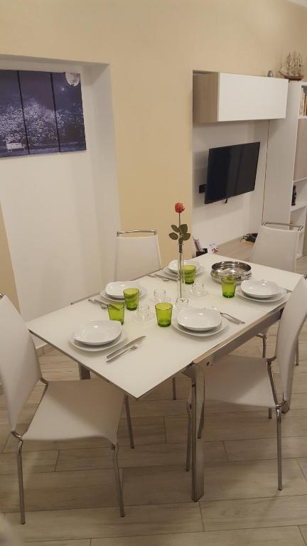 a white dining room table with white plates and chairs at Karina House-check in H 24 in Como