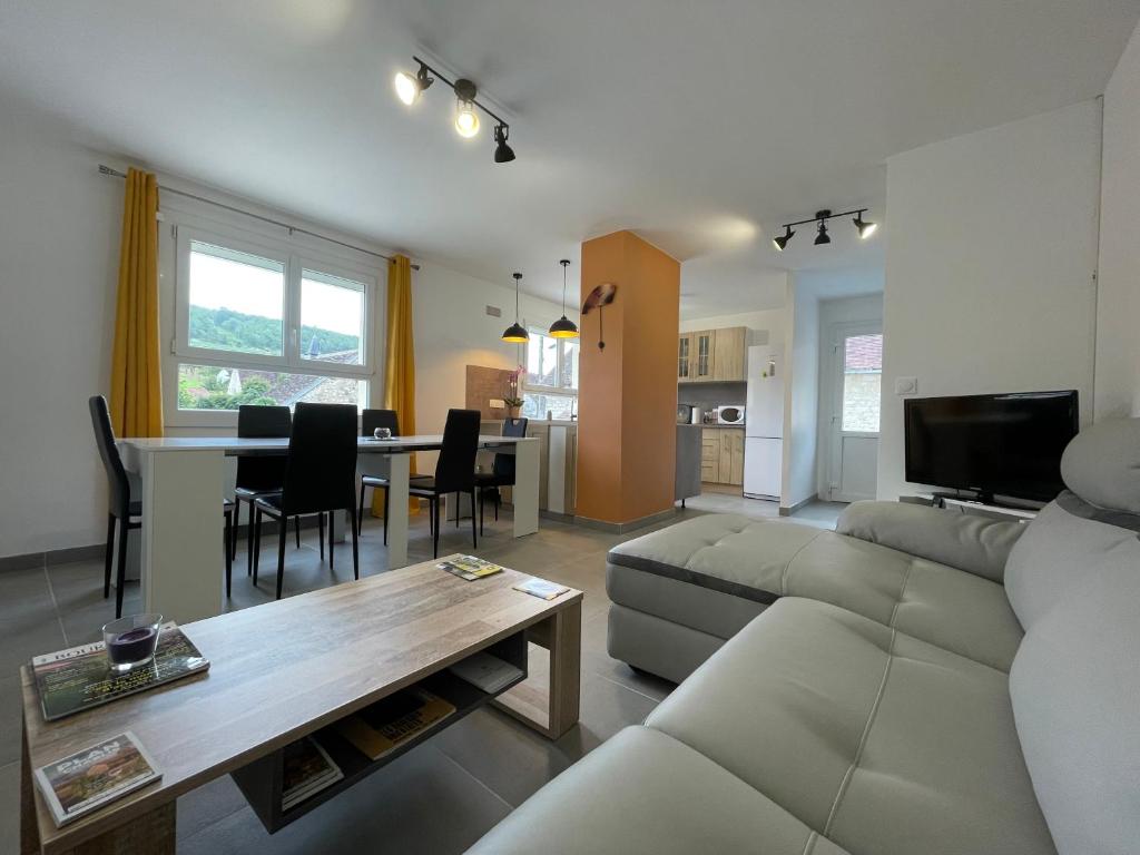 ein Wohnzimmer mit einem Sofa und einem Tisch in der Unterkunft Maison de campagne entre vigne et bois in Chablis
