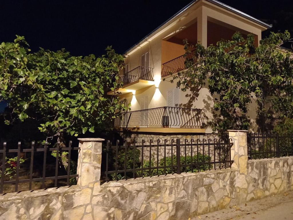 una casa con valla y balcón por la noche en Apartman Noni Biograd na Moru, en Biograd na Moru
