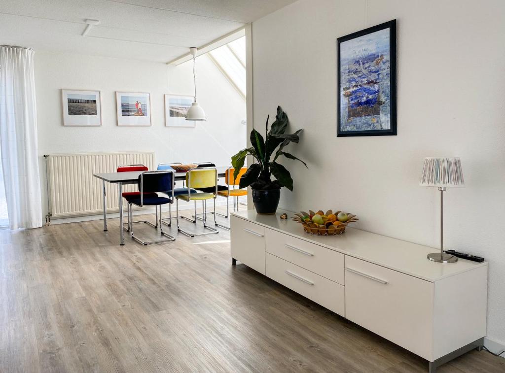 een witte woonkamer met een tafel en stoelen bij Hello Zeeland - Vakantiehuis Zwin 182 in Breskens