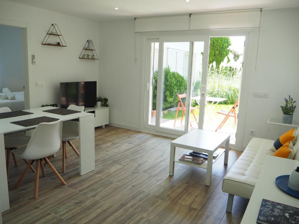 ein weißes Wohnzimmer mit einem Tisch und einem Sofa in der Unterkunft Apartament amb piscina i aparcament - Baixos amb jardinet in Calella de Palafrugell