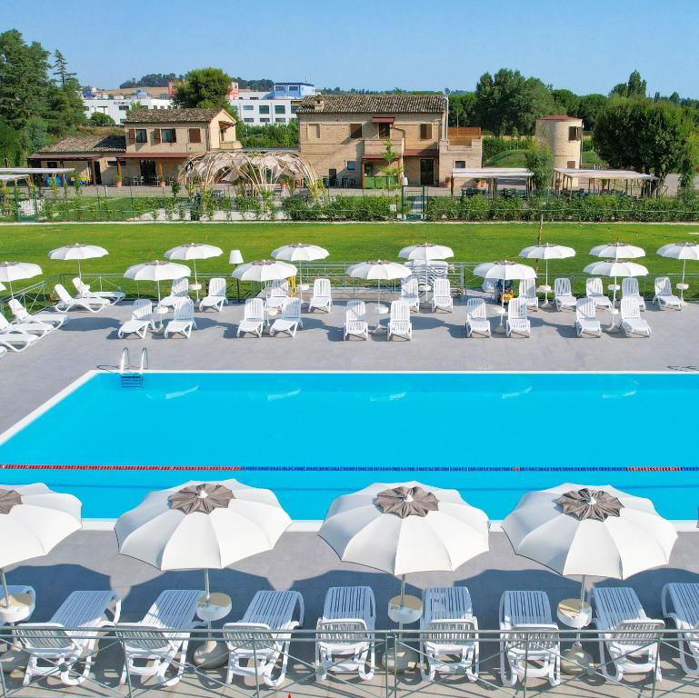 un gruppo di sedie e ombrelloni accanto alla piscina di Moretti Village - B&B a Civitanova Marche