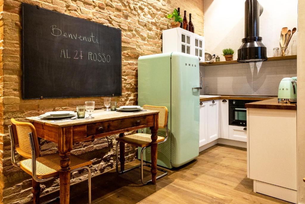 eine Küche mit einem Tisch und einem grünen Kühlschrank in der Unterkunft Al 24 Rosso in Siena